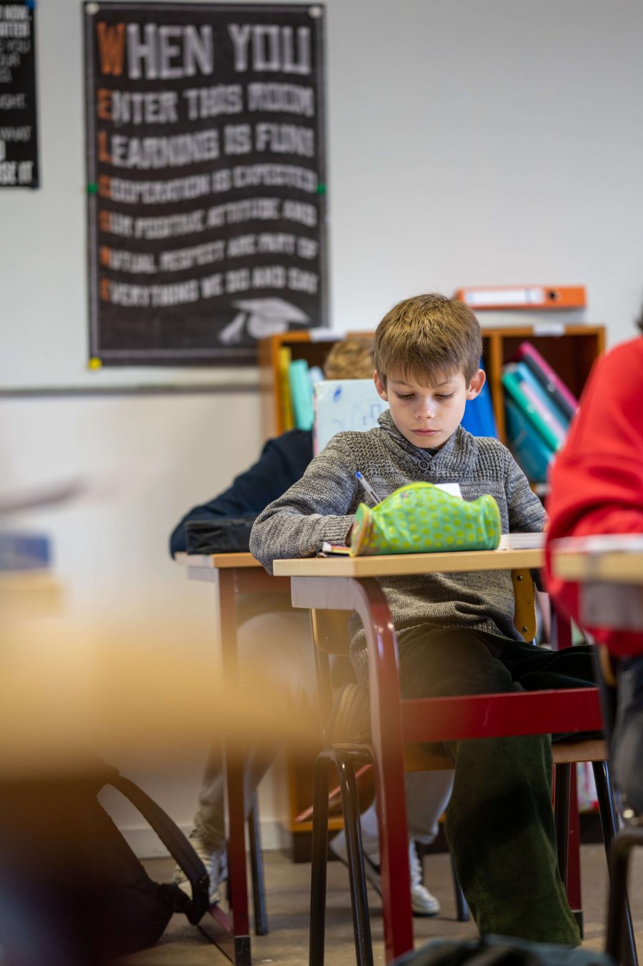 Een leerling werkt geconcentreerd aan zijn bank in de klas